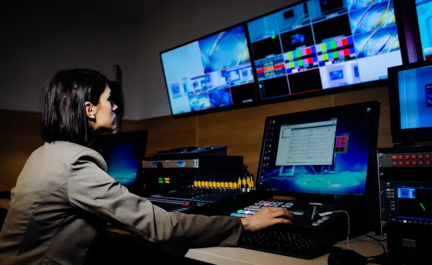 Person in tv studio adjusting the media screens 