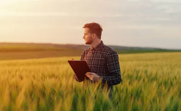 Person stands in a field holding a clipboard