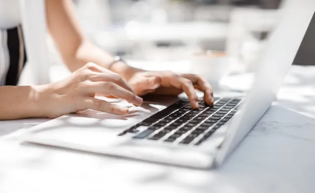 Kvinna som skriver på ett tangentbord på en laptop