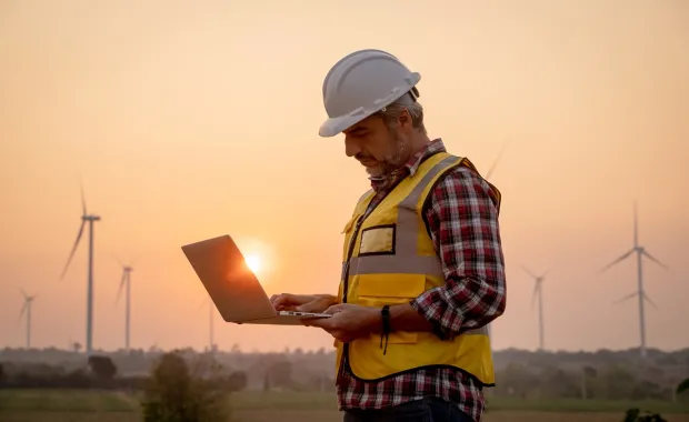 an engineer using a laptop in a wind farm