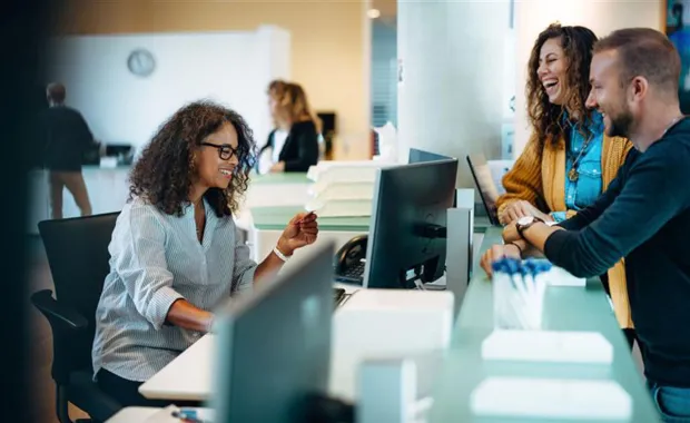 three coworkers talking at desk