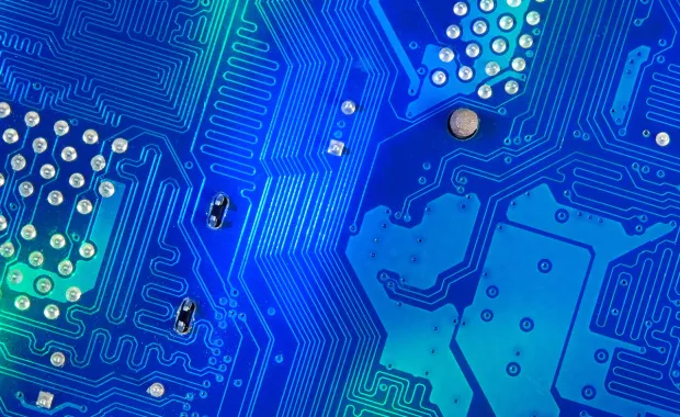 Nærbilde av blått kretskort med ledningsbaner og komponenter.