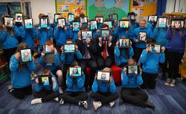 School children in a group show their faces on their ipads 