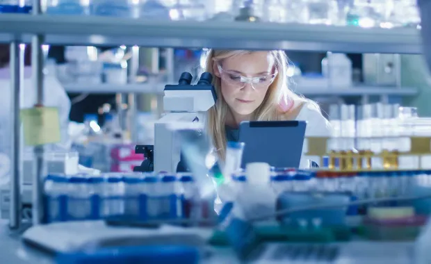 A scientist seating in a lab working with a microscope