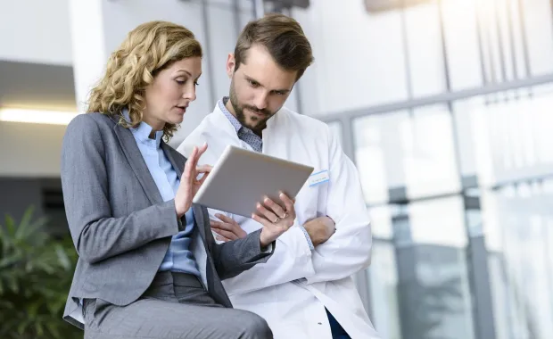Physician and professional reviewing data on smart tablet