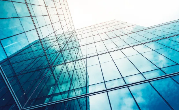 Moderni lasirakennus, jonka heijastavat pinnat muodostavat abstraktin, verkostomaisen rakenteen.