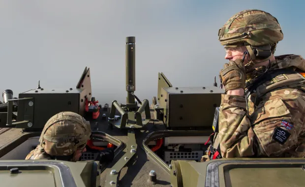 Soldater som sitter i en stridsvagn och den ena talar i sin kommunikationsutrustning