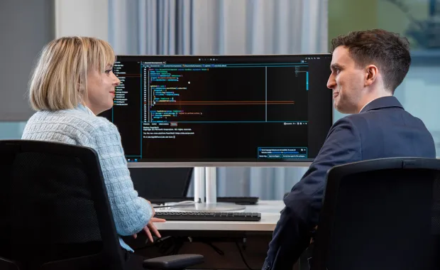 Två kollegor som sitter framför en skärm med kod