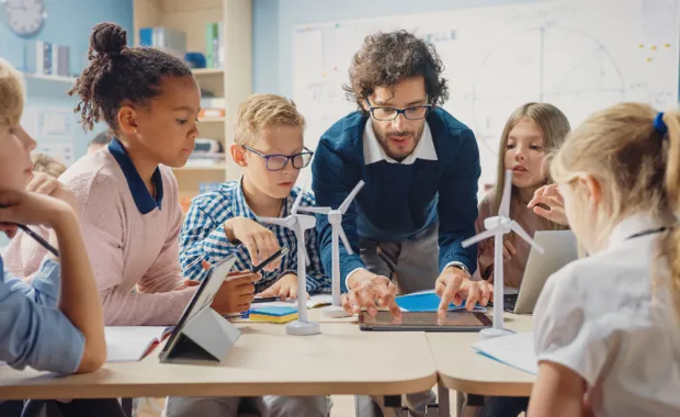Teacher shows school children model of wind turbine