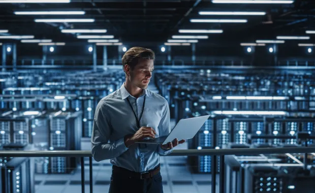 Technologist standing using a laptop in a server room