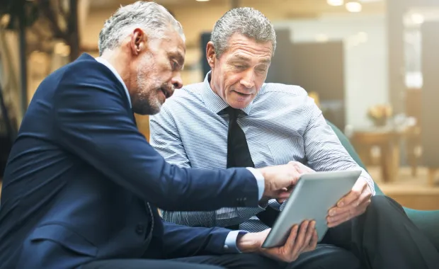 Two businessmen discussing info on a tablet