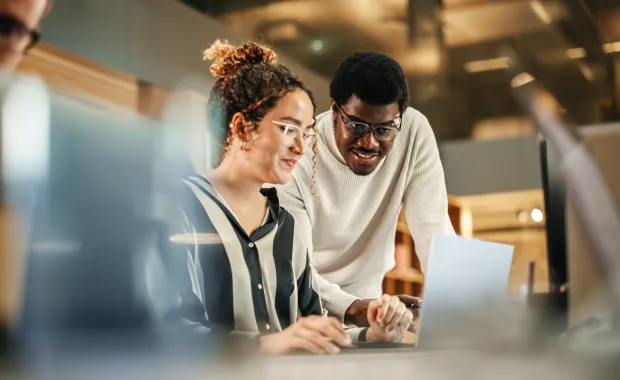 Two colleagues looking at a laptop