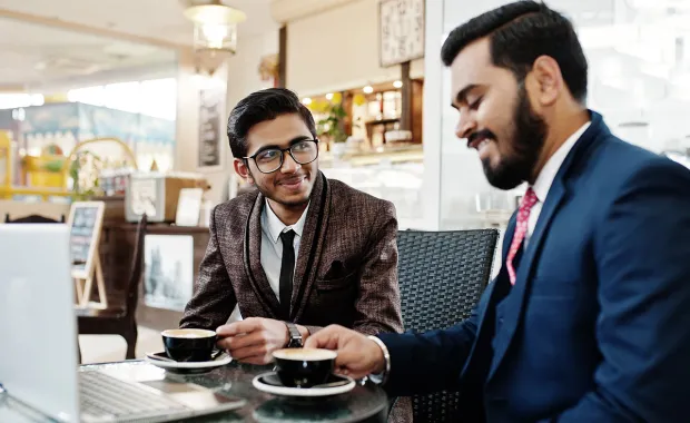 Two people wearing business attire drinking coffee in a cafe