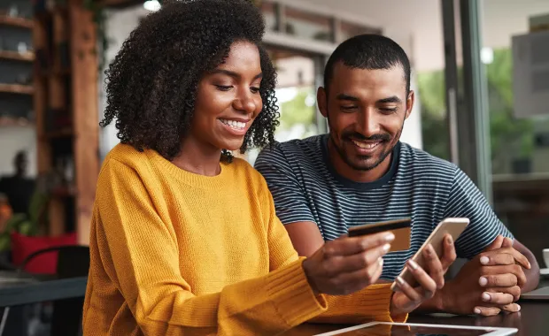 Two people smiling whilst looking at a phone and payment card