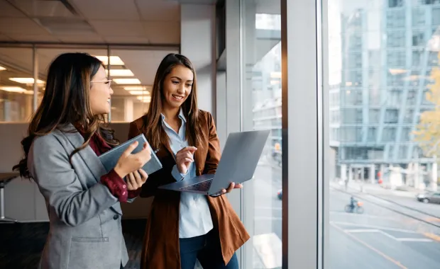 Two smiling business women looking at a laptop