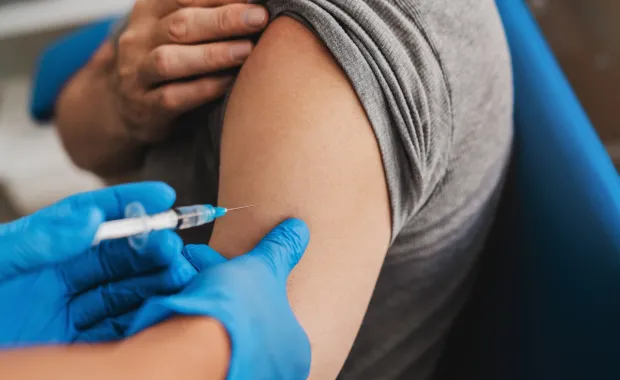 Person receiving a vaccine in arm from medical professional