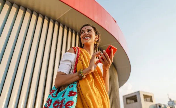 Young indian woman wearing sari using mobile phone outdoors