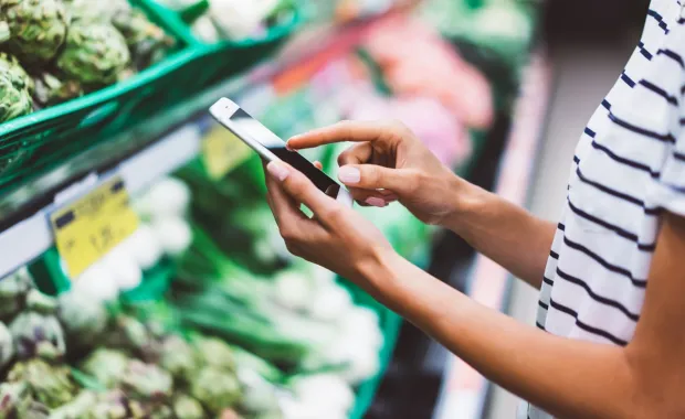 Woman shopping in a supermarket using her smartphone