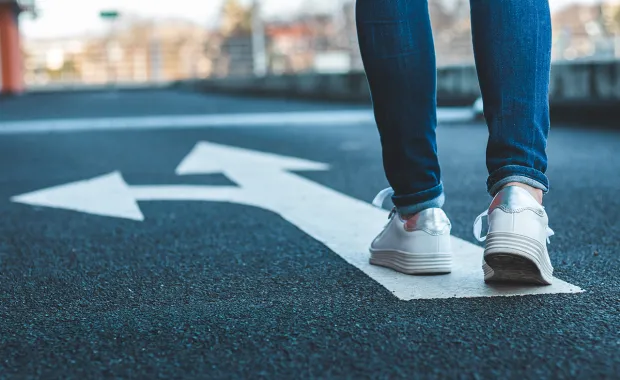 Eine Person geht auf einer Straße an einer markierten Abzweigung entlang, passend zum Thema Change Management im Arbeitsalltag
