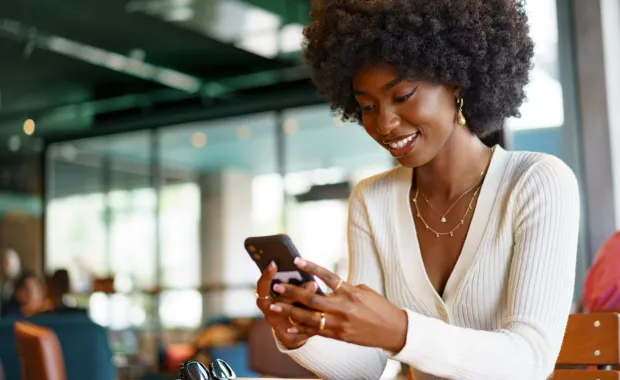 Kuvituskuva: hymyilevä nainen katsoo älypuhelintaan