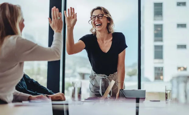 Två kvinnliga kollegor ger high five till varandra
