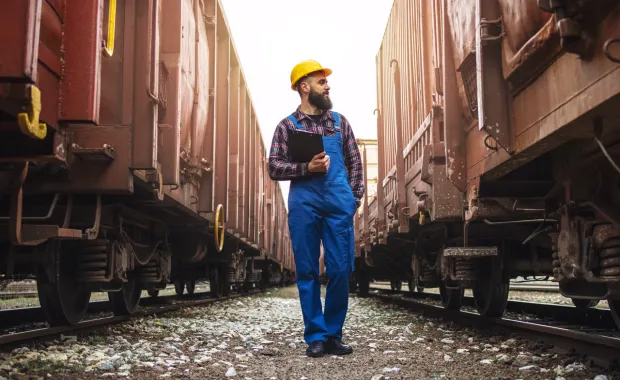Workman walking between two freight trains