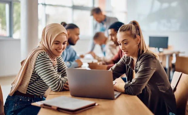 Young people looking at a laptop in a learning environment