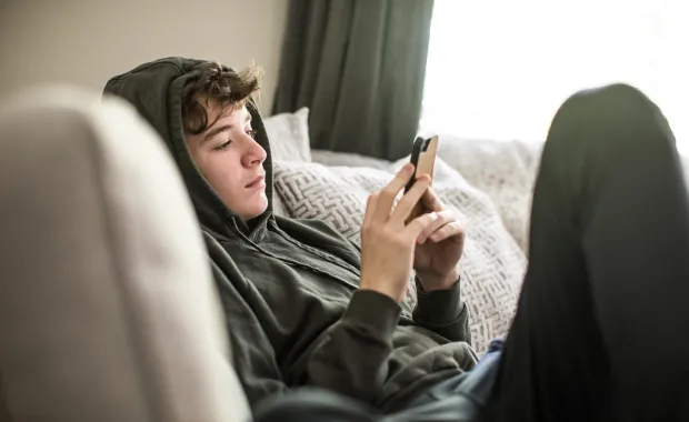 Jeune garçon portant un sweat à capuche et utilisant un téléphone portable