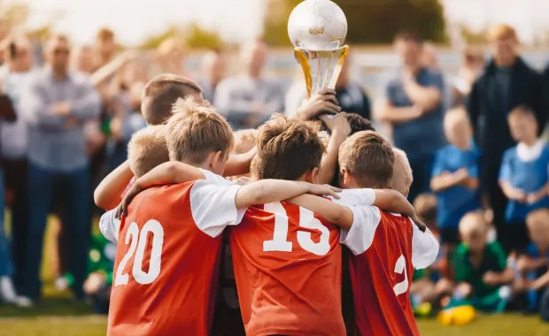 Youth soccer team huddled holding up a trophy