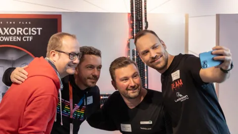 Vier Männer auf dem CTF Event umarmen sich und machen ein gemeinsames Selfie
