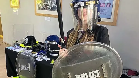 Female student trying on Police riot uniform at CGI Young Dreamers event