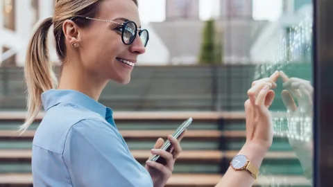 Smiling female consultant with phone touching screen