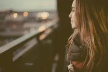 Ung kvinna står med ett lätt leende och blickar ut genom ett fönster