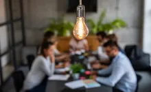 Team sat round conference table with a light bulb above