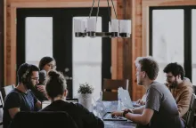 Team av unga kvinnor och män sitter vid ett cafébord och jobbar tillsammans