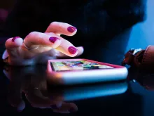 Hand med rosa nagellack och en ring på ringfingret knappar på sin smartphone som ligger i närbild