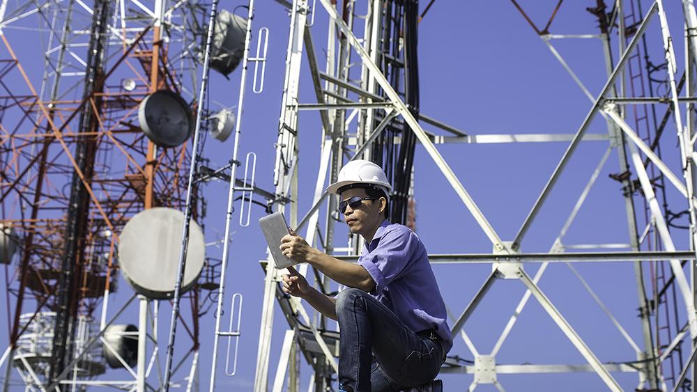 A worker uses technology on communications equipment, representing the CGICarnotsatCarnotSat .solution