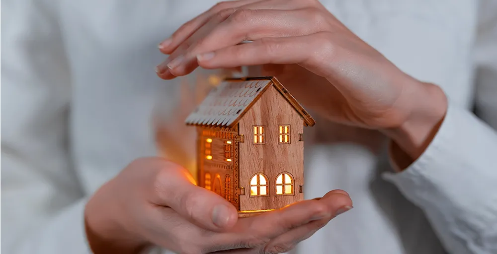 person holding a lighted model of a wooden house