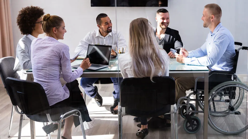 A CGI member in a wheelchair sat at a table with a group of colleagues