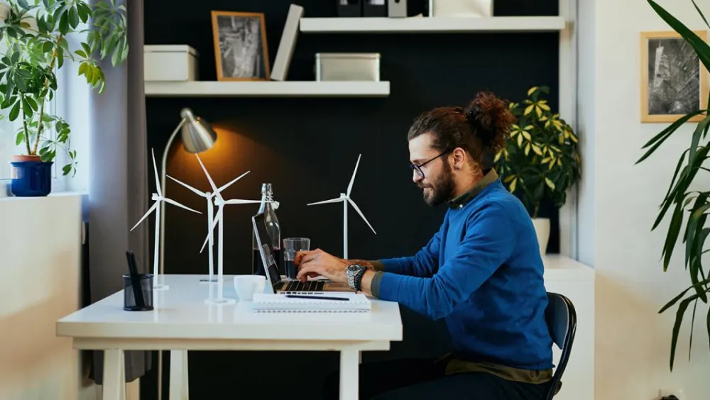 man working from home with small model wind turbines on his desk