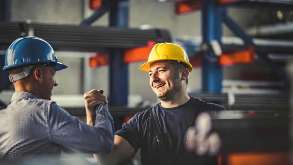 To arbeidere som tar hverande i hendene i en fabrikk