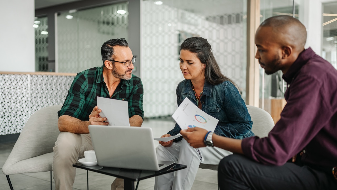 three people sitting together and working