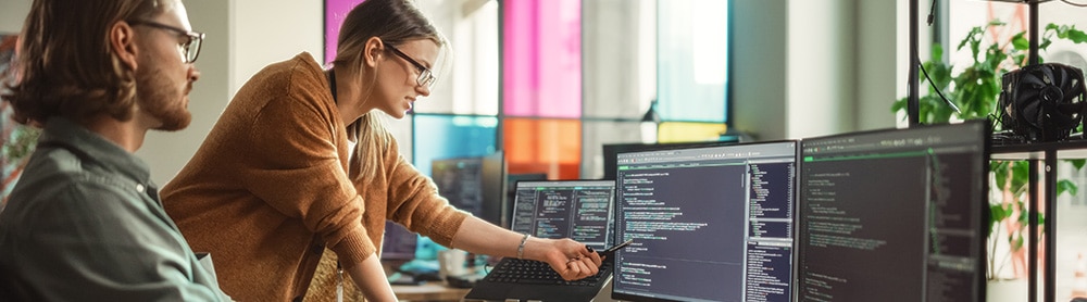 Two people looking at code on a computer