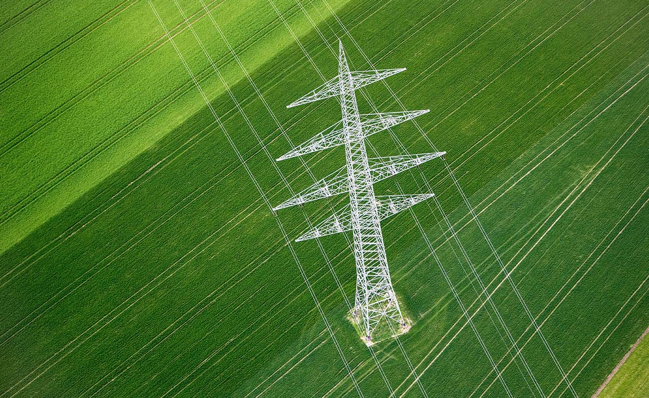 Høyspentmast sett ovenfra over grønt jorde med kraftlinjer. Høyspentmast sett ovenfra over grønt jorde med kraftlinjer.