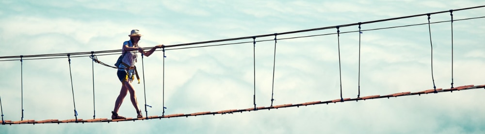 Eine Frau geht über eine Hängebrücke