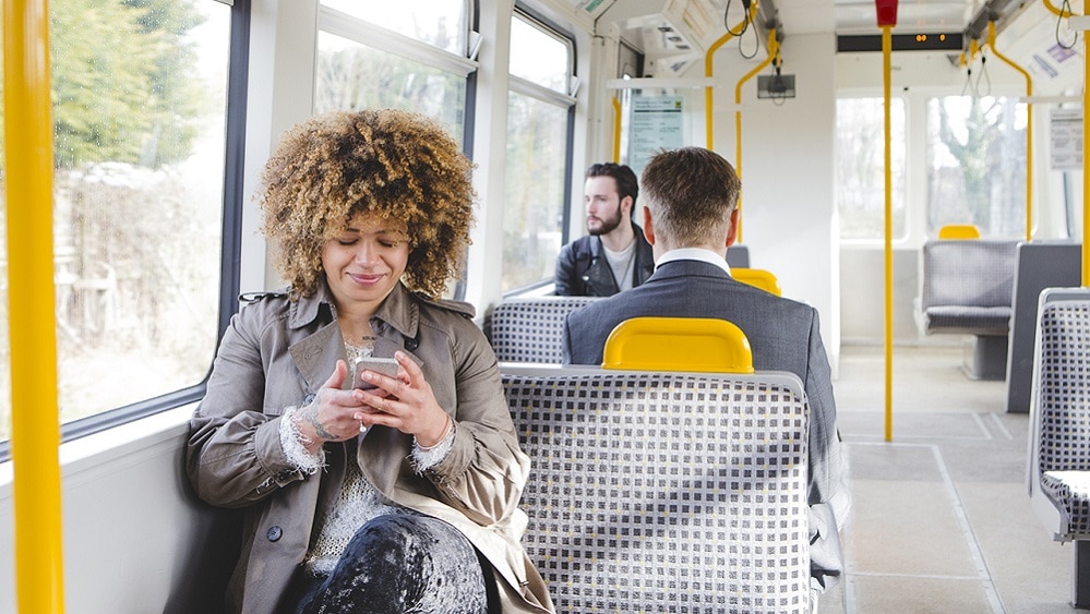 Woman sat on West Midlands Tram looking at her phone