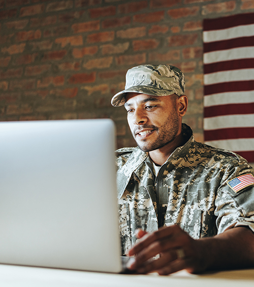 military service member looking at a laptop 