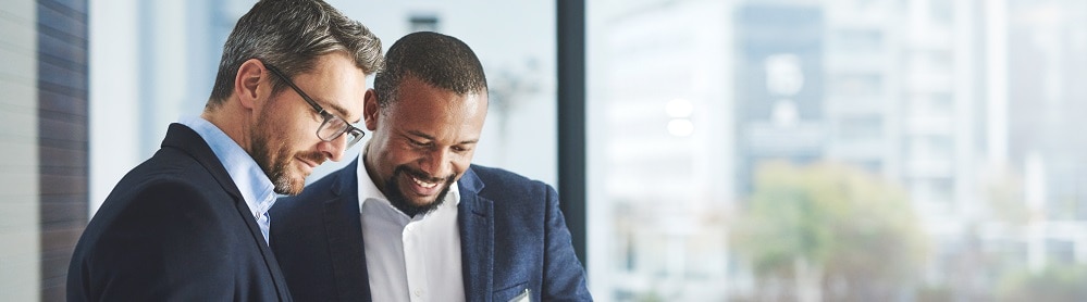 continuous-improvement-salesforce-managed-services Two men standing and talking while looking at a table