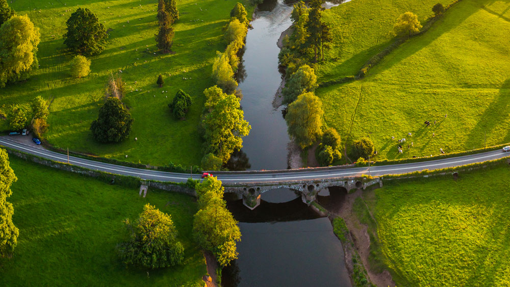 Drone view of a river cutting across a green countryside landscape