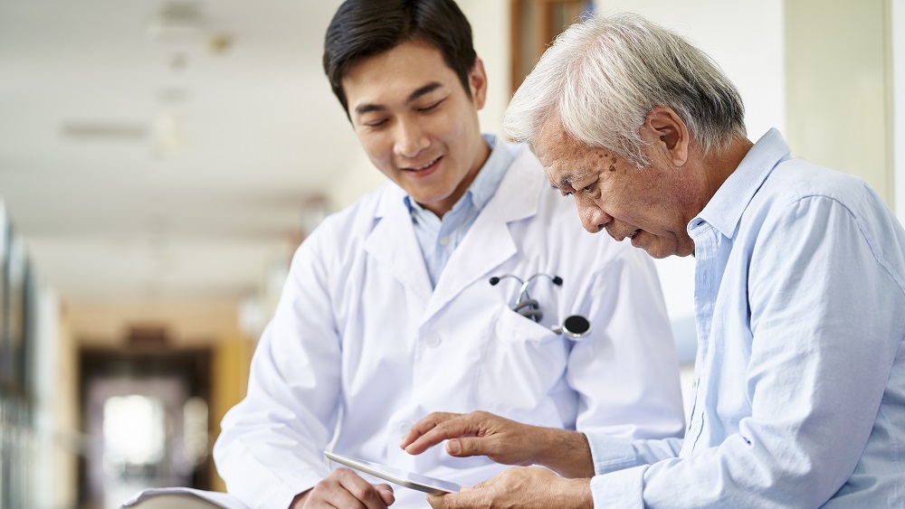 Health provider and older patient reviewing data on a tablet